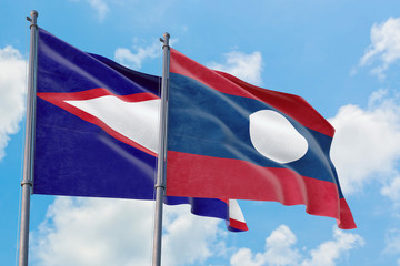 Laos and American Samoa flags waving in the wind against white cloudy blue sky together. Diplomacy concept, international relations.