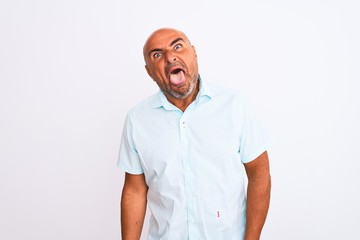Middle age handsome man wearing casual shirt standing over isolated white background sticking tongue out happy with funny expression. Emotion concept.
