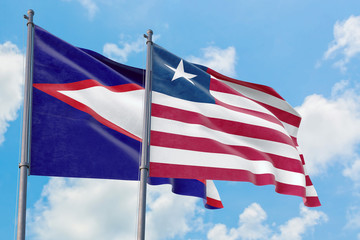 Liberia and American Samoa flags waving in the wind against white cloudy blue sky together. Diplomacy concept, international relations.