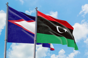 Libya and American Samoa flags waving in the wind against white cloudy blue sky together. Diplomacy...