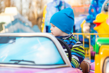 Obraz na płótnie Canvas Little baby riding a car in amusement park. A small driver. The child is driving a toy car. Amusement park for children