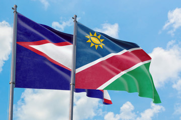 Namibia and American Samoa flags waving in the wind against white cloudy blue sky together. Diplomacy concept, international relations.