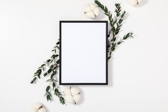 Composition of flowers and eucalyptus. Photo frame, eucalyptus branches and leaves, cotton flowers on white background. Valentines Day, Easter, Happy Women's Day. Flat lay, top view, copy space