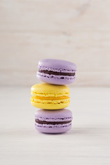 different colored macarons. Colorful French or Italian macarons on white wood table with copy space. Plate with macaroon cookie dessert.