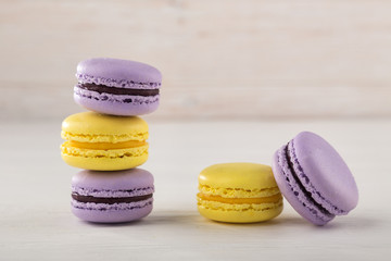 different colored macarons. Colorful French or Italian macarons on white wood table with copy space. Plate with macaroon cookie dessert.