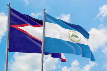 Nicaragua and American Samoa flags waving in the wind against white cloudy blue sky together. Diplomacy concept, international relations.