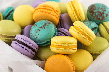 different colored macarons. Colorful French or Italian macarons on white wood table with copy space. Plate with macaroon cookie dessert.