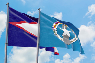 Northern Mariana Islands and American Samoa flags waving in the wind against white cloudy blue sky...
