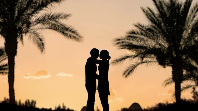 kissing couple silhouettes at palms sunset beach background