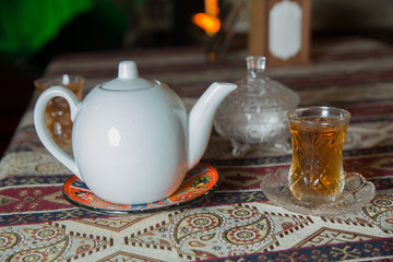 Tea in Azerbaijani traditional armudu pear-shaped glass . Azerbaijan black tea .white sugar cubes . White kettle and sugar bowl . Ceramic white teapot . Azerbaijani aromatic tea in armudu cup .