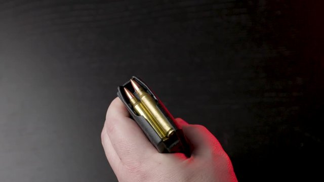 Loading an AR15 magazine, black background