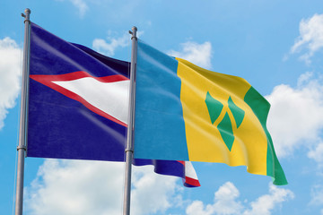 Saint Vincent And The Grenadines and American Samoa flags waving in the wind against white cloudy blue sky together. Diplomacy concept, international relations.