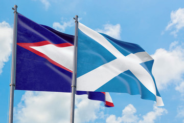 Scotland and American Samoa flags waving in the wind against white cloudy blue sky together. Diplomacy concept, international relations.