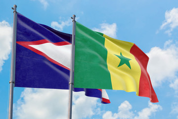 Senegal and American Samoa flags waving in the wind against white cloudy blue sky together. Diplomacy concept, international relations.