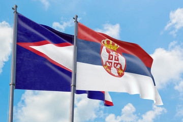 Serbia and American Samoa flags waving in the wind against white cloudy blue sky together. Diplomacy concept, international relations.