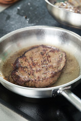Grilled steak in a pan. Cooking beef steak on grill pan. Cooking in the kitchen in a wok with smoke and boiling oil. Close up view. Space for text 
