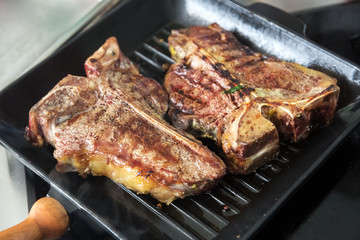 Grilled steak in a pan. Cooking beef steak on grill pan. Cooking in the kitchen in a wok with smoke and boiling oil. Close up view. Space for text 