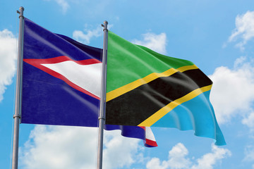 Tanzania and American Samoa flags waving in the wind against white cloudy blue sky together. Diplomacy concept, international relations.
