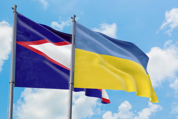 Ukraine and American Samoa flags waving in the wind against white cloudy blue sky together. Diplomacy concept, international relations.