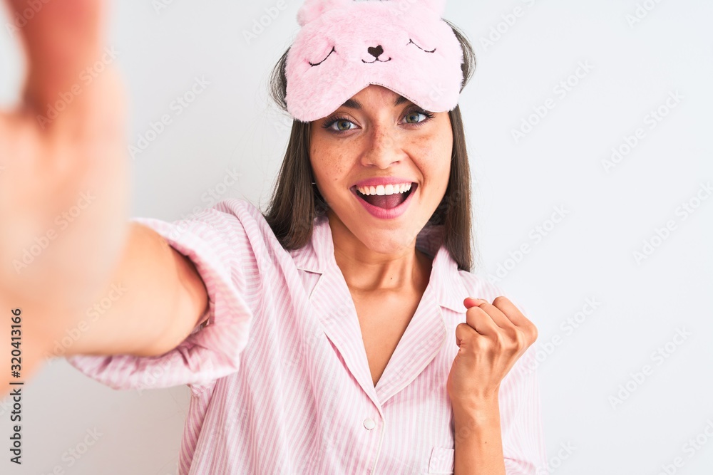 Poster Young woman wearing sleep mask make selfie by camera over isolated white background screaming proud and celebrating victory and success very excited, cheering emotion