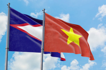 Vietnam and American Samoa flags waving in the wind against white cloudy blue sky together. Diplomacy concept, international relations.