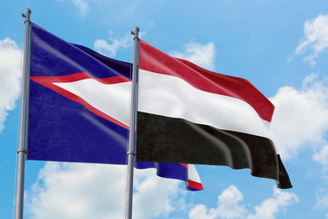 Yemen and American Samoa flags waving in the wind against white cloudy blue sky together. Diplomacy concept, international relations.
