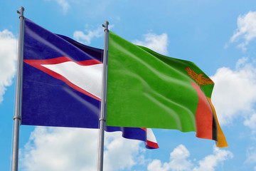 Zambia and American Samoa flags waving in the wind against white cloudy blue sky together. Diplomacy concept, international relations.