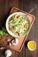 Fusilli pasta with basil pesto sauce and cherry tomatoes, sprinkled with shredded cheese