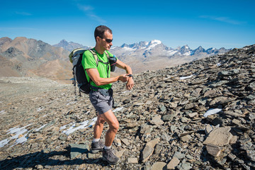 skyrunner training over the mountains watching heart rate monitor. italian Alps. Gran Paradiso National Park, Italy