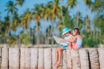 Adorable little girls with big map of island on beach