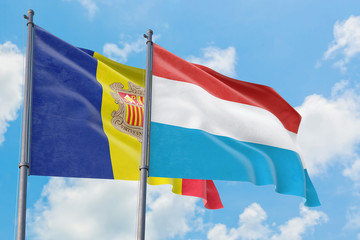Luxembourg and Andorra flags waving in the wind against white cloudy blue sky together. Diplomacy concept, international relations.