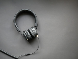 Modern black headphones on color background