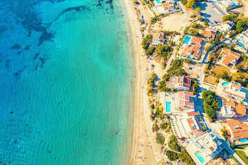 Aerial view of Coral Bay beach - popular beach with clear sea water and comfortable sandy beach, many tourists, sunbeds with umbrellas in Peyia village, Cyprus.