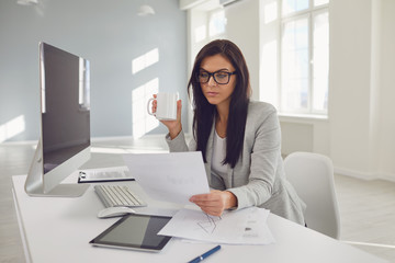 Business woman in glasses confident sitting at a table in the workplace in the office