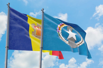 Northern Mariana Islands and Andorra flags waving in the wind against white cloudy blue sky together. Diplomacy concept, international relations.