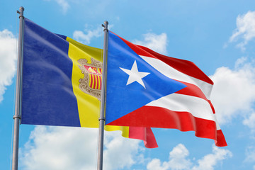 Puerto Rico and Andorra flags waving in the wind against white cloudy blue sky together. Diplomacy concept, international relations.
