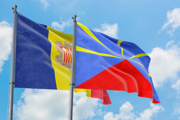 Reunion and Andorra flags waving in the wind against white cloudy blue sky together. Diplomacy concept, international relations.