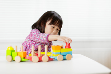 Fototapeta na wymiar toddler girl playing creative toy blocks at home against white background