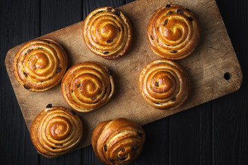 Puff curls with fruit, jam, berries, sweet soft cheese. Puff pastry on a wooden board and a black wooden table. Fresh French Homemade Puff curls pastry. Warm Fresh Buttery Rolls.