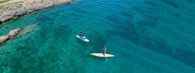 Aerial drone ultra wide photo of friends practising in SUP or Stand Up Paddle in tropical exotic...