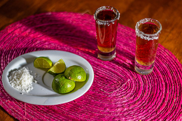 dos caballitos de tequila con limon y sal y una botella