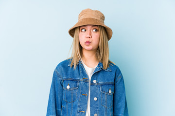 Young blonde caucasian woman isolated blows cheeks, has tired expression. Facial expression concept.