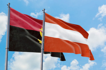 Austria and Angola flags waving in the wind against white cloudy blue sky together. Diplomacy concept, international relations.