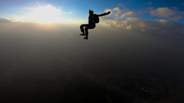 Skydivers making a sit fly position at the sunset