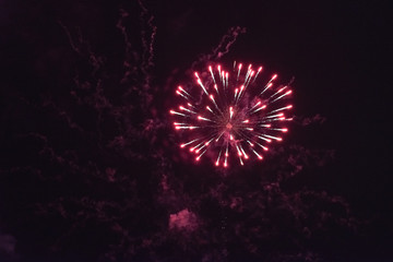 Beautiful inexpensive red fireworks against the dark sky. With smoke.
