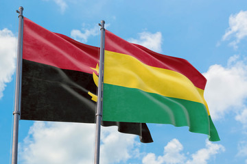 Bolivia and Angola flags waving in the wind against white cloudy blue sky together. Diplomacy concept, international relations.