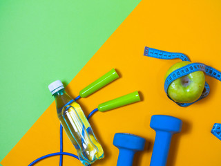 flat lay photo of fitness equipment over orange and green backgound. top view