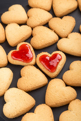 Heart shaped cookies decorated for Valentine's Day. Free space for text. Two heart shaped cookies with jam on a black wooden table. Like postcard 