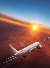 Commercial airplane jetliner flying above dramatic clouds in beautiful light. Travel concept.