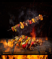 Tasty skewers on iron cast grate with fire flames.